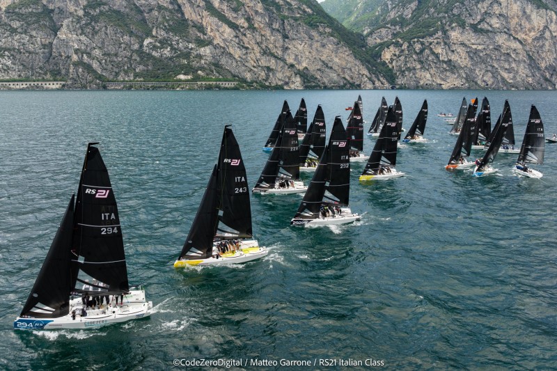 Grande attesa e di nuovo numeri da record per l’Act 4 della RS21 Cup Yamamay, in concomitanza con il Campionato Italiano e l’attribuzione del 1° trofeo “King of The Lake”, in programma, dal 25 al 27 agosto, nella splendida cornice di Riva del Garda con la regia della Fraglia Vela Riva. Saranno infatti ben trentatré gli armatori sulla linea di partenza per la prima delle nove prove previste dal bando di regata.  Soddisfazione anche da parte del presidente della RS21 Italian Class Davide Casetti: «Sono entusiasta della risposta di partecipazione dei nostri armatori. L’evento è il preludio del Mondiale e quindi la tensione agonistica sale così come quella organizzativa. Il mio augurio è che tutti si divertano in acqua e fuori». Attesa anche per i nuovi armatori e per alcuni ritorni nella flotta RS21. Nello specifico: Alessio Marinelli con “Uji Uji” (Circolo Vela Porto Civitanova), Michele Ferrari “Whatever” (Verbano Yacht Club), Paul Fisk “Trigger” (Emsworth Saling Club Gb), Alexandra Agostini “Sibilla”(Cv Portocivitanova), Andrea Musone “Freccia Blu” (Club Nautico Rimi), Stefano Visintin “Kindako” (Yc Porto Piccolo Ts), Andrew Baker “Kalinda III” (Southport Yacht Club Main Beach Queensland AUS) e Alessandro Solerio “Lelagain for Emmara” (Yc Sanremo). Come anticipato a Riva del Garda ci sarà molta “carne al fuoco” a cominciare dalla assegnazione del titolo tricolore. Gianluca Grisoli, armatore e timoniere di “Beyond Freedom” (Cnam Alassio), vestirà i panni del defender con il titolo conquistato nella stagione 2022 a Marina di Puntaldia in Sardegna. Nei “Corinthian” defender è invece “CodeZero Sailing Team” di Vincenzo Liberati (Cn Sambenedettese) attuale leader anche della RS21 Cup Yamamay. Ma non solo titolo italiano anche perché l’Act4 di Riva del Garda diventa determinante per la conquista della RS21 Cup Yamamay 2023 prima dell’epilogo a Porto Rotondo in contemporanea con il Campionato del Mondo. Ci sarà quindi da attendersi grande battaglia con “Arvenis” di Davide Albertini Petroni  (Cn Loano) che si trova al comando della classifica provvisoria grazie agli ottimi piazzamenti sin qui ottenuti, ma con soli sette punti di vantaggio su “Fremito d’Arja” di Dario Levi (Cv Torbole) vincitore degli Act di Alassio e Torbole. Attenzione anche a “Stenghele” di Pietro Negri (Cv Torbole Tn), “Caipirinha” di Martin Reintjes (Fraglia Vela Desenzano Bs) primo a Rimini e “Das Sailing Team” di Alessandro Zampori (Cnam Alassio) pronti a recuperare posizioni. Nei “Corinthian” si conferma la lotta tutta marchigiana fra “CodeZero Sailing Team” di Vincenzo Liberati  e “Stick N’ Poke” di Federica Archibugi (Sef Stamura An) divisi da soli cinque punti: un nulla che con concederà passi falsi. Sul terzo gradino del podio, a sorpresa, il giovane team debuttante di “Ita 238” di Alessandro Venini e Riccardo Benvenuto (Lni Mandello del Lario). Infine giochi apertissimi nella prima edizione del “Trofeo King of The Lake” conteggiato sulle prove di Torbole e quella di Riva del Garda. Qui può succedere di tutto perché i primi tre, dopo la prima tappa, e cioè “Fremito d’Arja” (Dario Levi), “Torpyone” (Edoardo Lupi) e “Stenghele” (Pietro Negri) sono racchiusi in soli sette punti. A Riva del Garda non sarà però solo vela. Infatti, sabato 26 agosto alle ore 10, proposto dalla Commissione Sostenibilità della RS21 Italian Class, è in programma l’ennesimo incontro – in concomitanza con gli Act della RS21 Cup Yamamay – sui principi della sostenibilità e inclusione con particolare attenzione alle economie circolari. Temi da sempre cari alla RS21 Italian Class. L’incontro, moderato da Luca Giovannini della Commissione Sostenibilità e presidente di NOX Oceani, vedrà in apertura l’intervento del presidente Davide Casetti che presenterà l’attività futura in termini di sostenibilità e facendo il punto sul processo di certificazione ISO 20121 della classe RS21. Seguiranno poi gli interventi di Andrea Zuanetti, CEO di Up2You, che parlerà di sostenibilità e di compensazione delle emissioni di CO2: «Siamo orgogliosi di essere il partner di RS21 fin dall'importante decisione di rendere la sostenibilità ambientale parte integrante della loro mission – ha anticipato Zuanetti -. La nostra esperienza e competenza nella sostenibilità ambientale ci consentono di garantire che le azioni intraprese da RS21 abbiano un impatto positivo reale sull'ambiente, creando al contempo un significativo beneficio sociale. Attraverso il nostro impegno congiunto, miriamo a fare una differenza concreta e a dimostrare l'eccellenza italiana nella promozione di uno sviluppo sostenibile e responsabile». A seguire interverranno: Claudia Grasso, responsabile della Fondazione Peso Positivo per parlare dei disturbi del comportamento alimentare e Alberto Antognozzi di MatchPlat per parlare di piattaforme per la ricerca e la selezione di partner sostenibili.  Ma ecco la “top ten” della classifica generale della RS21 Cup Yamamay dopo le tappe di Alassio, Rimini e Torbole (21 prove con scarto): 1) “Arvenis” (Davide Albertini Petroni  - Cn Loano) p. 68; 2. “Fremito d’Arja” (Dario Levi - Cv Torbole) p.75; 3. “Stenghele” (Pietro Negri - Cv Torbole Tn) p.80; 4. “Caipirinha” (Martin Reintjes – Fraglia Vela Desenzano Bs) punti 82; 5.“Das Sailing Team” (Alessandro Zampori - Cnam Alassio) p.84; 6. “Gioia” (Carlo Brenco - Cv Malcesine Vr) p. 111; 7.  “Beyond Freedom” (Gianluca Grisoli - Cnam Alassio) p.114; 8. “CodeZero Sailing Team” (Vincenzo Liberati - Cn Sambenedettese) p. 144; 9.“Stick N Poke” (Federica Archibugi - Sef Stamura An) p.149; 10. “Diva” (Andrea Battistella - Uv Maccagno Va) p. 153. Il podio della Corinthian: 1. “CodeZero Sailing Team” (Vincenzo Liberati) p144.; 2. “Stick N Poke” (Federica Archibugi) p.149; 3. “Ita 238” (Alessandro Venini) p.196.  La ranking competa su: https://www.hubsail.it/ranking/RS21/2023/ Nel “Trofeo King of The Lake” al comando, dopo la prima delle due tappe, si trova “Fremito d’Arja” (Dario Levi) con 37 punti davanti a “Torpyone” (Edoardo Lupi) con 40 e “Stenghele” (Pietro Negri) con 44. La RS21 Cup Yamamay si articola su 5 Act. Dopo il debutto di Alassio, Rimini, Torbole e Riva del Garda epilogo alla grande a Porto Rotondo, dal 27 al 30 settembre, con la disputa anche e soprattutto del primo Campionato del Mondo RS21 in Italia.