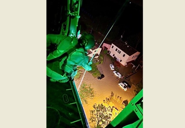 Un operatore di volo a bordo di un elicottero della Marina Militare mentre, nel corso della scorsa notte, recupera con il verricello persone rimaste isolate dalla piena