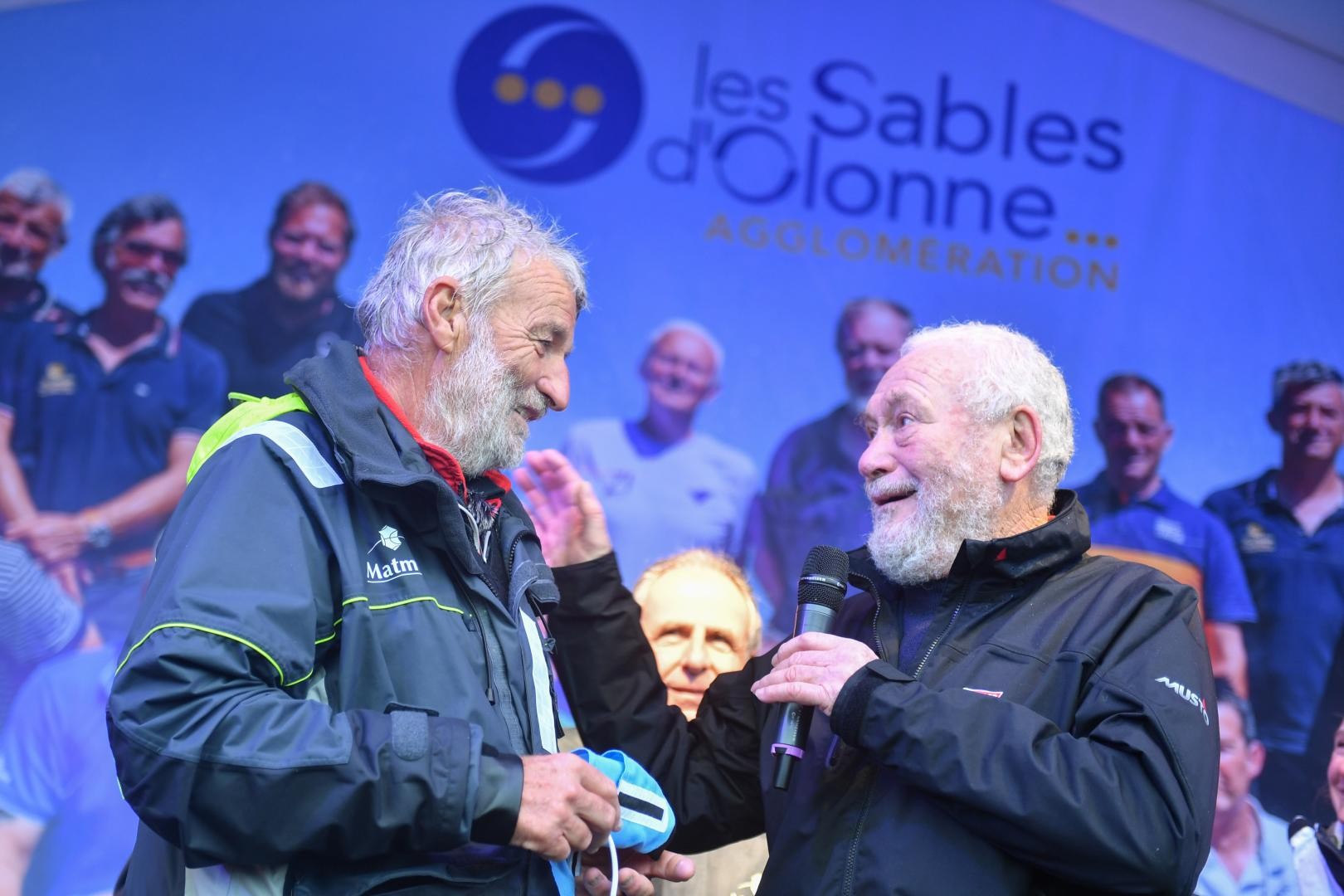 Jean-Luc Van Den Heede (left) being congratulated by Sir Robin Knox-Johnston after winning the 2018/19 Golden Globe Race. Photo credit: Christophe Favreau/PPL/GGR